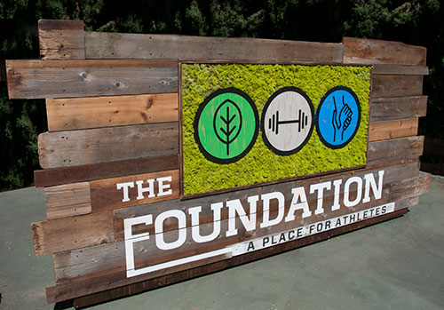 Custom logo wrapped in preserved moss and incorporated into a reclaimed wood living wall by Urban Garden Studio