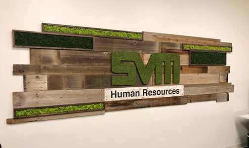 Create a stunning visual display with a custom moss logo created from preserved moss and incorporated into a reclaimed wood living wall, complete with preserved moss boxes featuring reindeer moss & hand painted logo by Urban Garden Studio