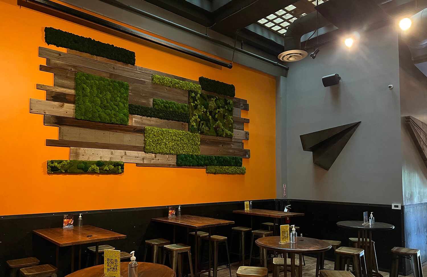 Colorful preserved moss wall panels created from cushion moss, mood moss and reindeer moss are incorporated with reclaimed wood and mounted on a brightly painted wall for restaurant art.