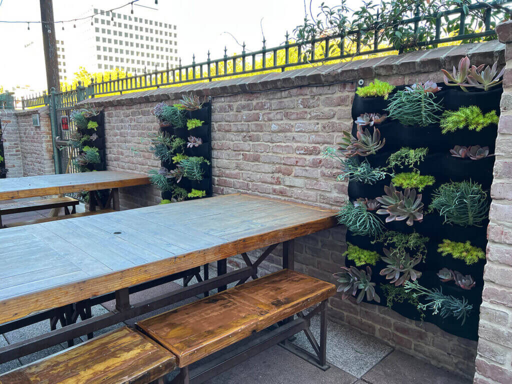 Elevate your outdoor patio with stunning vertical wall planters featuring vibrant succulents by Urban Garden Studio.