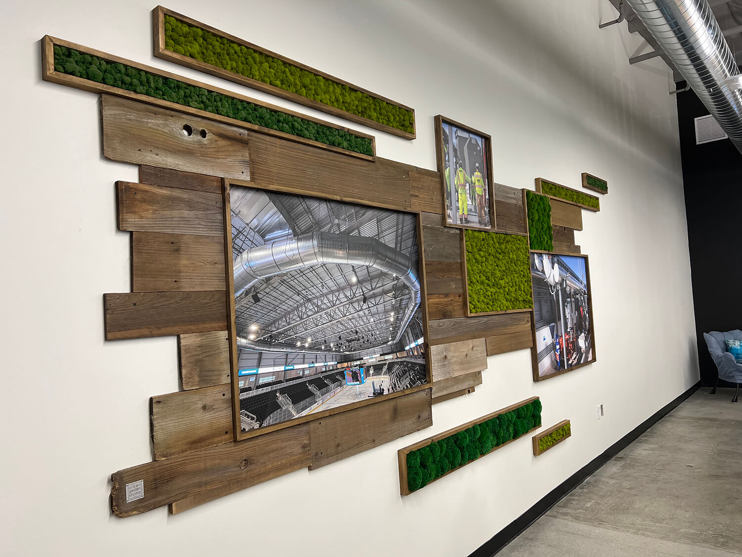 Custom office photos framed with rustic wood displayed on reclaimed wood wall adorned with preserved moss boxes, creating unique and sustainable office art display by Urban Garden Studio.